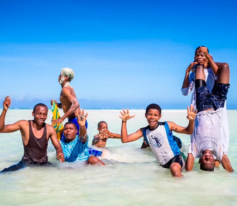 Friends splashing and playing in shallow turquoise water on a sandbar